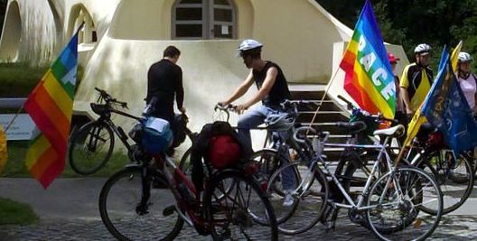Radfahrer mit Regenbogenfriedensfahnen.